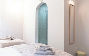 A hotel room with a large arched doorway, a bed with a folded towel, a bedside table, and a mirror on the wall. - St Andrews by Guestz (Lytham St. Anne's)