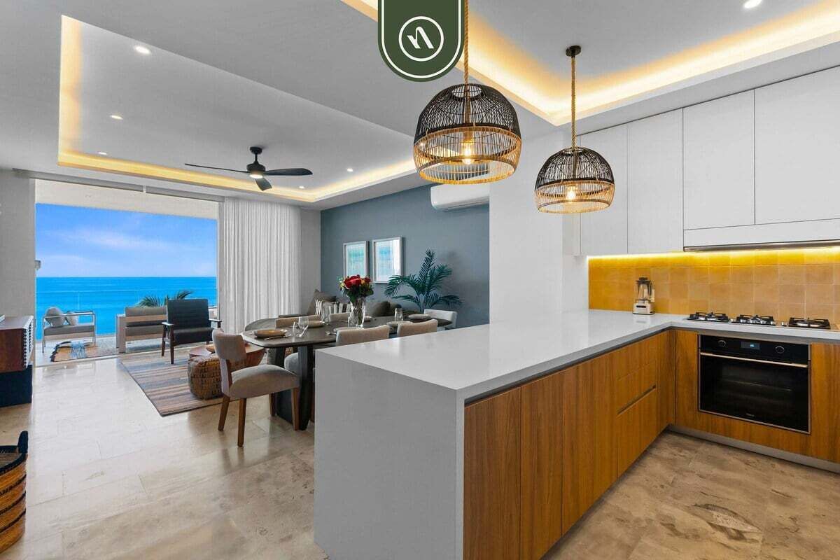 A modern kitchen with a central island, wooden cabinets, and pendant lighting.