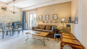 Een gezellige woonkamer met een stenen muur, een houten tafel, een bank en een ventilator.