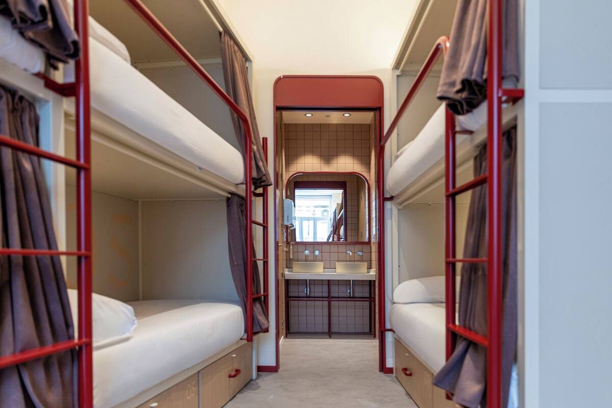 A bunk room with two beds, a small sink, and a mirror.