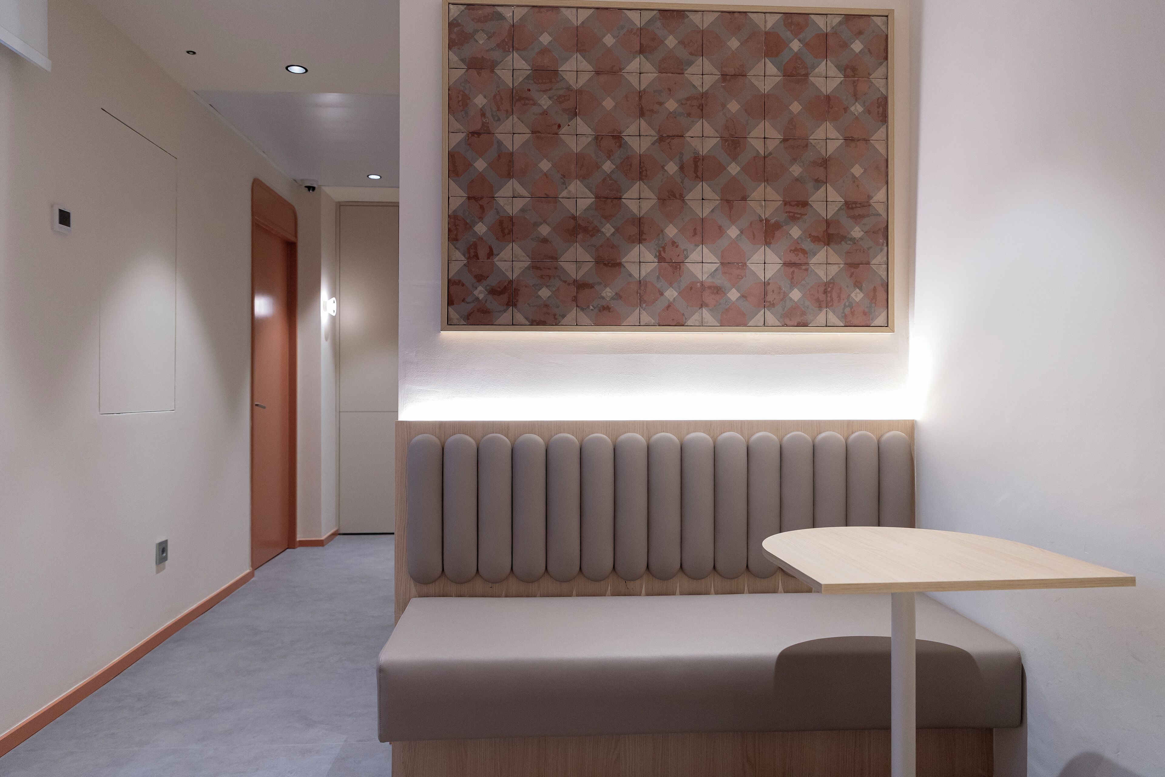 A modern hotel lobby with a seating area, a patterned wall, and a hallway.