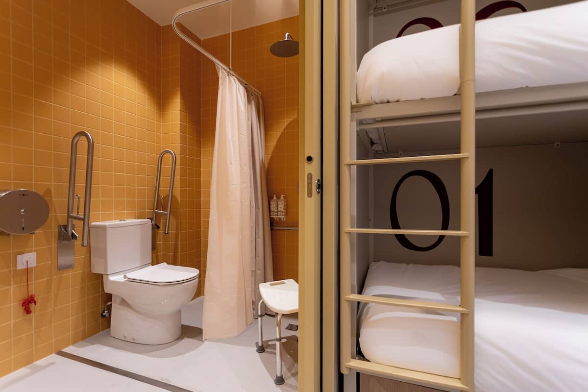 A bathroom with a toilet, shower, and bunk beds.