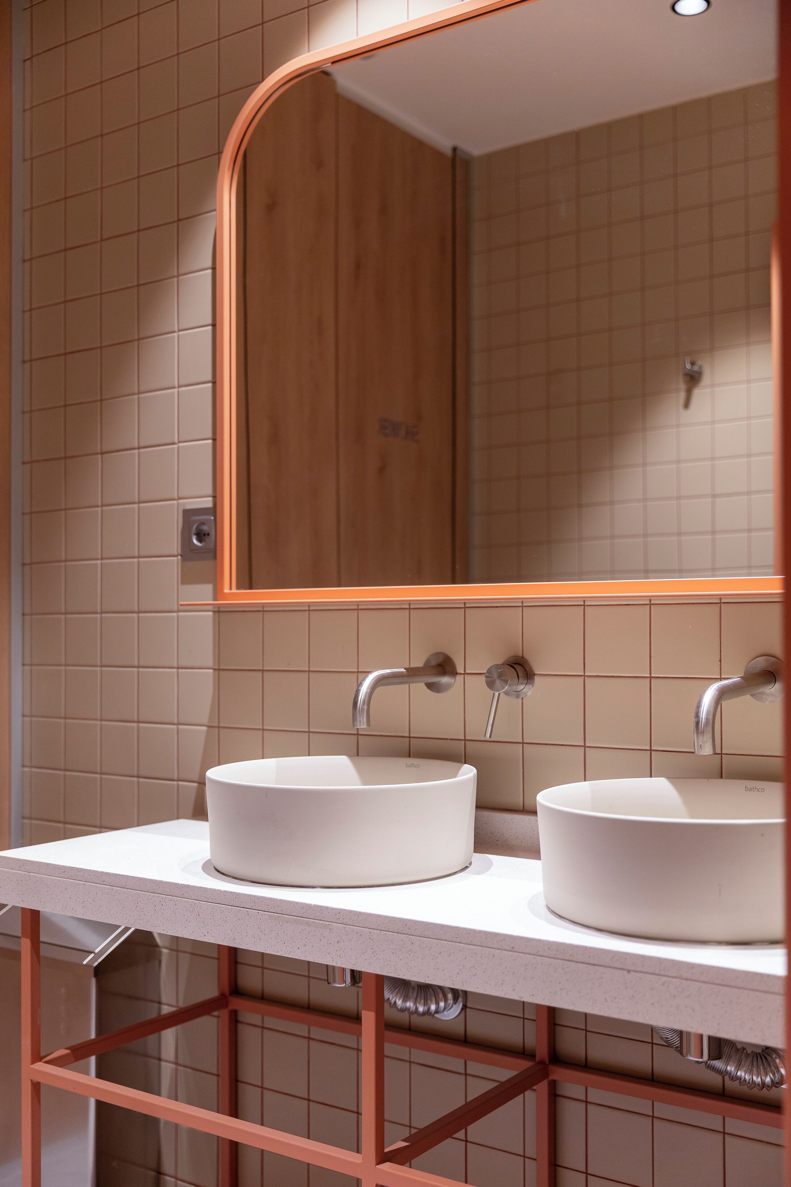 A bathroom with two sinks, a wooden mirror, and a tiled wall.