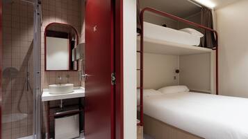 A compact hotel room with a shower, sink, and a bunk bed.