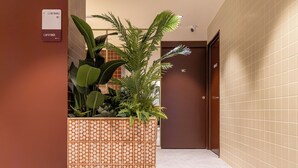 A hallway with a plant planter, a sign indicating coworking and WC facilities, and a door labeled "WC". - The Central House Valencia Mercado Central (Valencia)