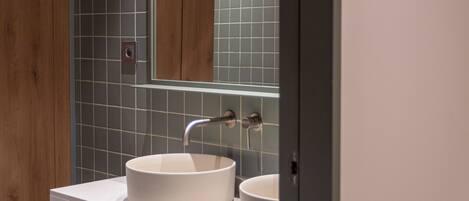 A modern bathroom with two sinks, a large mirror, and a wooden door.