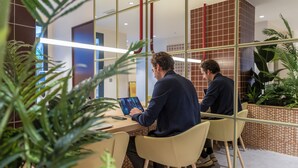 A modern indoor space with glass partitions, a wooden desk, and yellow chairs. - The Central House Valencia Mercado Central (Valencia)