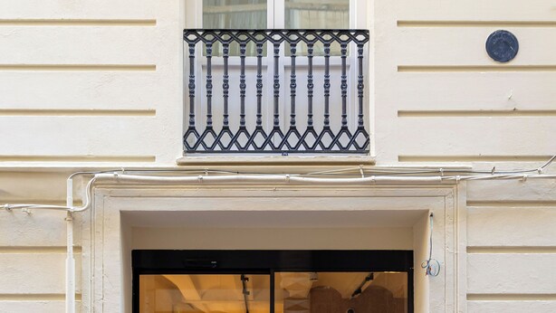 A cafe with outdoor seating, a glass door entrance, and a small balcony above the door. - The Central House Valencia Mercado Central (Valencia)
