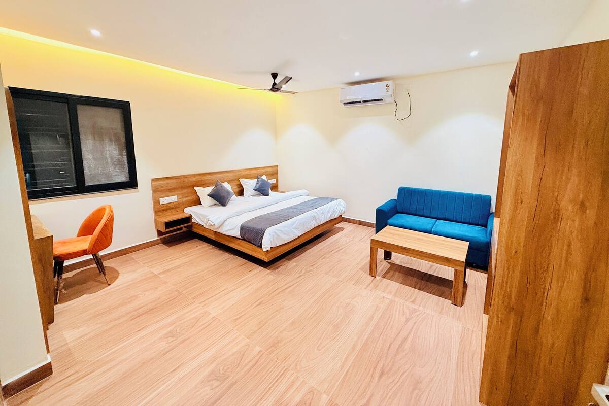Una habitación compacta con una cama, un sofá azul, una mesa de madera y una silla.