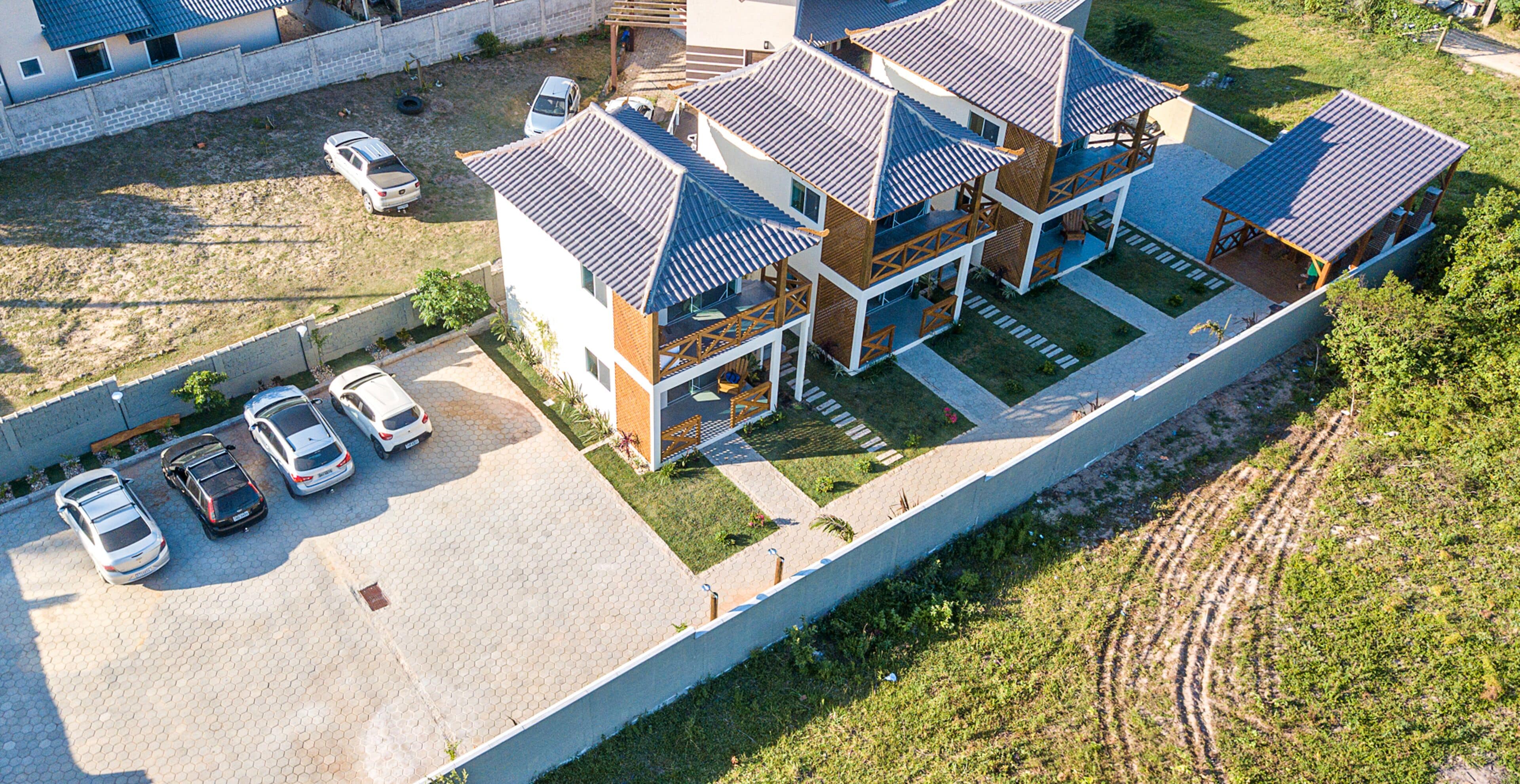 A multi-story residential building with a tiled roof, a parking area with several cars, and a surrounding grassy area.