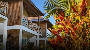 Un immeuble à plusieurs étages doté d’un balcon, entouré d’une végétation tropicale luxuriante.