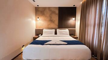 A hotel room with a large bed, two bedside tables, a phone, and a nightstand.