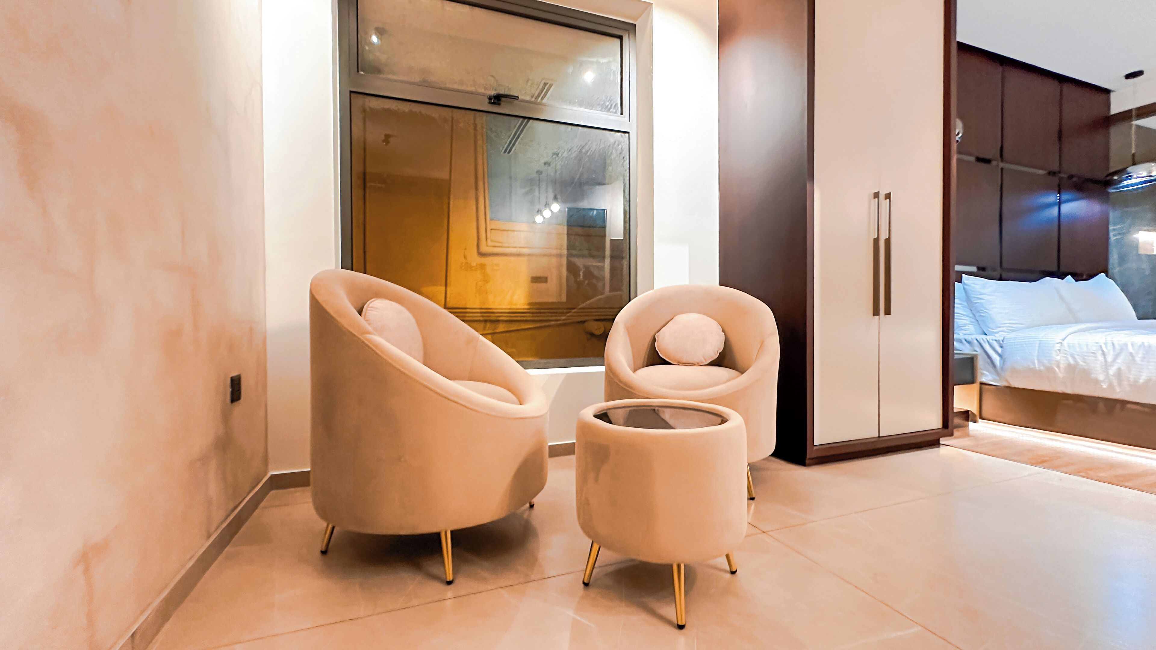 A modern bedroom with a large bed, a wardrobe, and two armchairs.