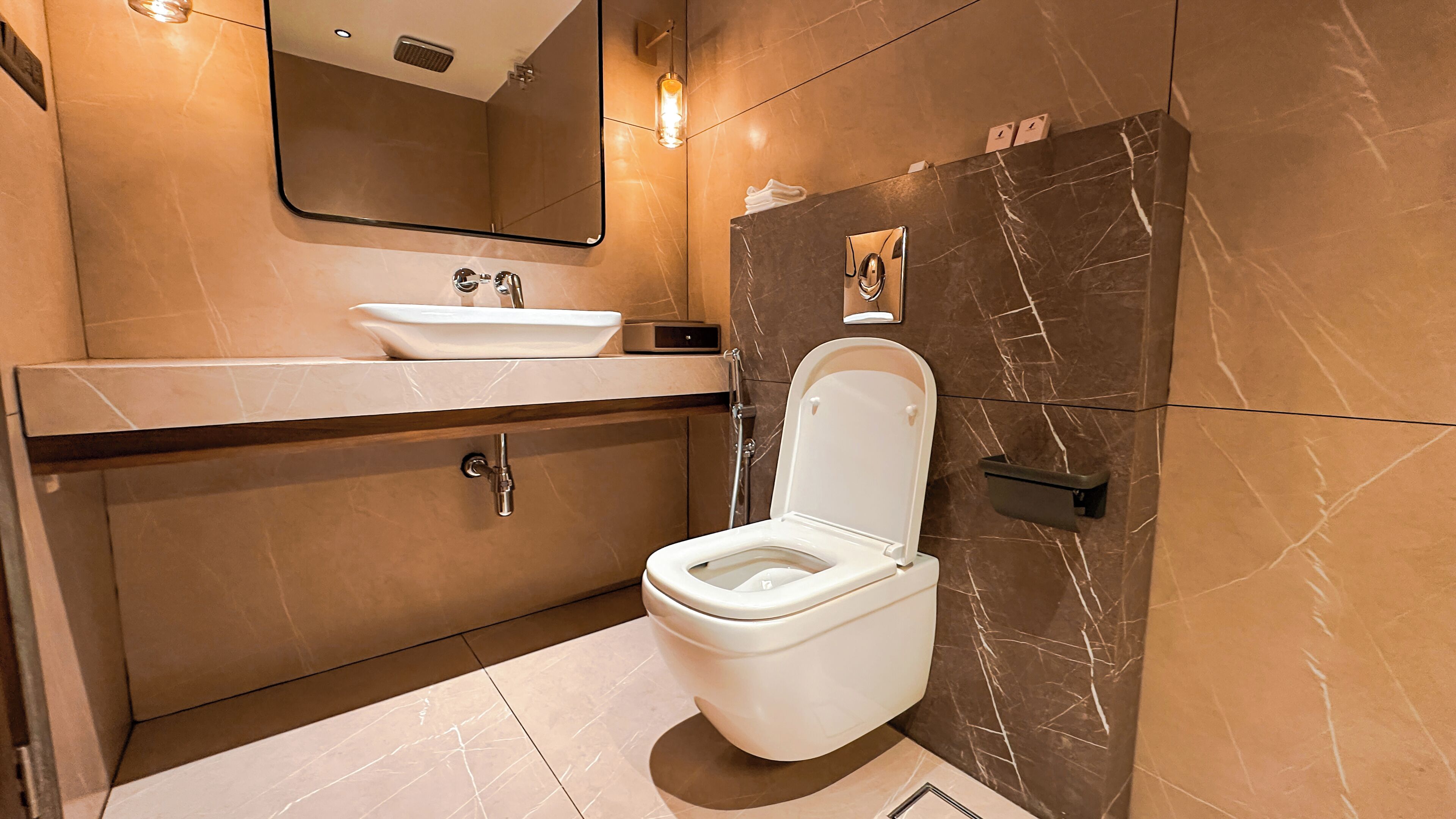 Un baño moderno con inodoro blanco, lavabo y espejo.