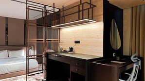 Une chambre d’hôtel moderne équipée d’un lit, d’un bureau avec un miroir, d’une machine à café et d’une prise électrique.