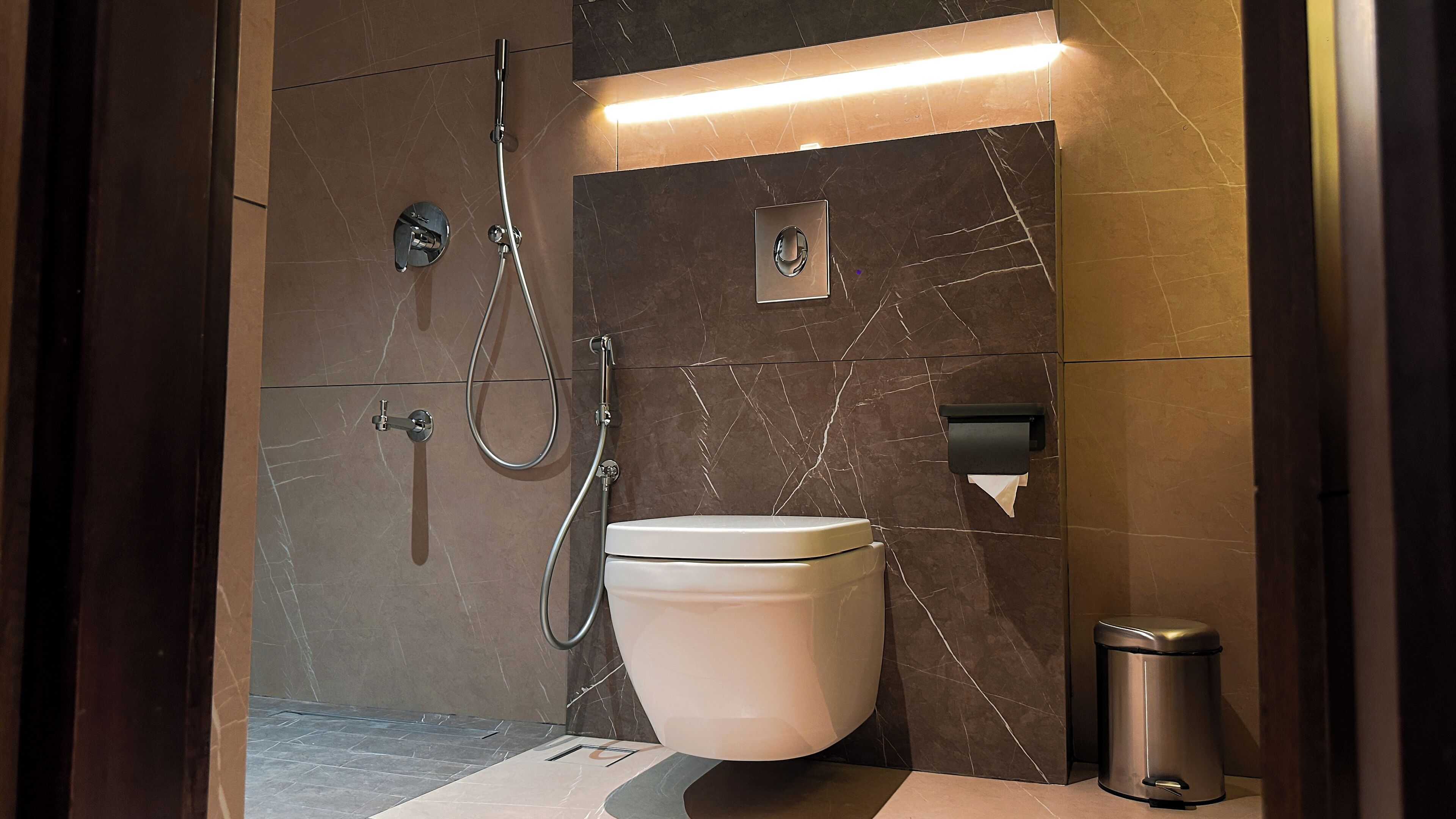 A modern bathroom with a toilet, a shower, and a hand dryer.