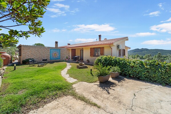 A house with a stone wall, a paved patio, and a garden.