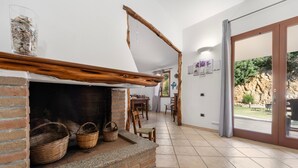 A fireplace with baskets, a wooden ceiling beam, and a view of the outdoors.