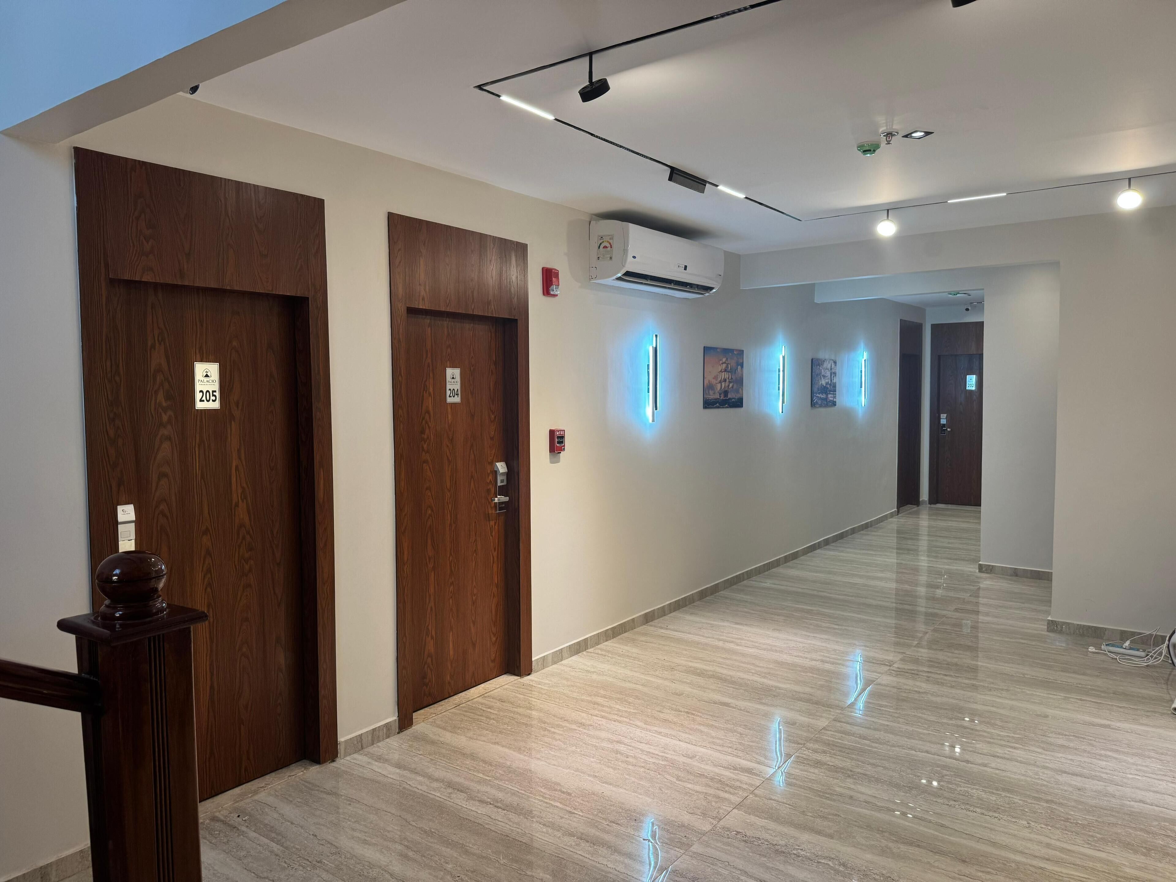 A hotel hallway with wooden doors, numbered 205 and 204, and a modern air conditioning unit.