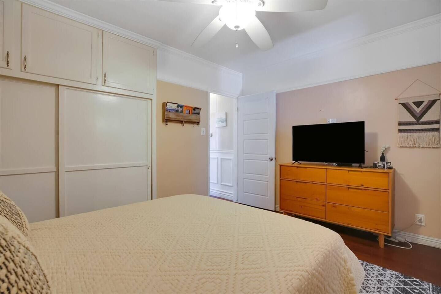 Un dormitorio con cama, armario, televisor y cómoda.