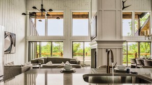 A spacious kitchen with a large island, a built-in sink, and a dining area with a high ceiling and large windows. - Luxe Home - Heated Pool, Hot Tub & Mountain Views! (Sevier County)