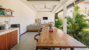 A modern kitchen with a wooden table, built-in cabinets, and a ceiling fan. - Sari Uma Canggu By Hospitality Bali (Canggu)