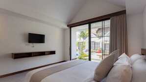 A bedroom with a large bed, a mounted TV, and a sliding glass door leading to a patio. - Sari Uma Canggu By Hospitality Bali (Canggu)