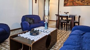 A living room with a sofa, a coffee table, and a dining area with a table and chairs. - Casa Bianca Villaputzu (Villaputzu)