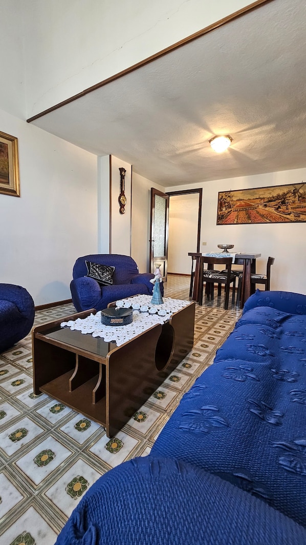 A living room with a sofa, a coffee table, and a dining area with a table and chairs.