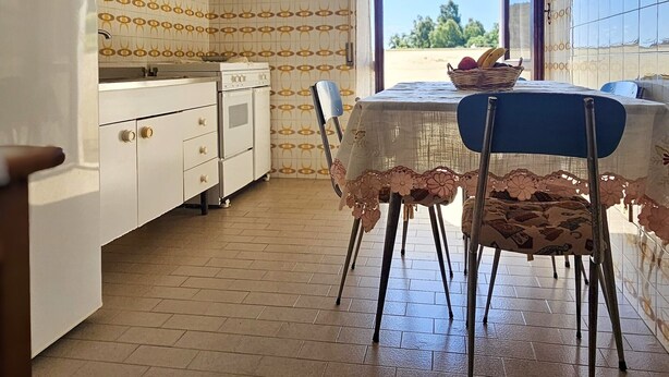 A kitchen with a dining area, a window with a view, and a ceiling fan. - Casa Bianca Villaputzu (Villaputzu)