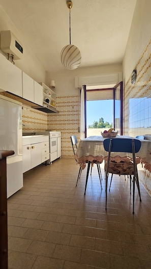 A kitchen with a dining area, a window with a view, and a ceiling fan.