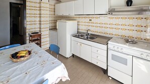 A compact kitchen with white cabinets, a sink, a stove, and a refrigerator. - Casa Bianca Villaputzu (Villaputzu)