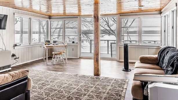 Una habitación amplia con techo alto, ventanas grandes, un rincón de descanso acogedor y un espacio para comer.