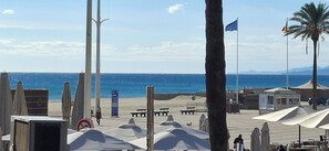 A beachside area with umbrellas, a palm tree, and a kiosk.