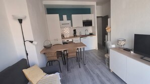 Un salon moderne comprenant un canapé, un téléviseur et un coin repas avec une table et des chaises.
