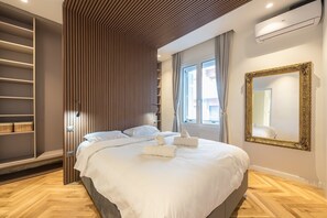 Ein modernes Schlafzimmer mit Bett, Einbauschrank und einem großen Spiegel.