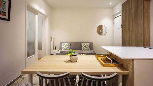 A modern kitchen with a wooden dining table, two chairs, a small plant, and a built-in wooden cabinet. - Spacious & Well Designed•2BR Apartment in Pangrati (Athina)