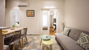 A modern living room with a sofa, a dining table with chairs, and a small green table. - Spacious & Well Designed•2BR Apartment in Pangrati (Athina)