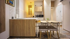 A modern kitchen with a wooden island, white tiles, and a dining area with two chairs. - Spacious & Well Designed•2BR Apartment in Pangrati (Athina)