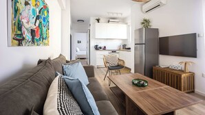 A modern living room with a sofa, coffee table, and artwork on the wall. - Bright Stylish 2BR | Acropolis View Balcony | King Bed (Athina)