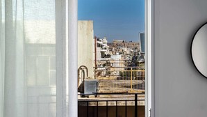 A balcony with a view of a cityscape, including a prominent building in the distance. - Bright Stylish 2BR | Acropolis View Balcony | King Bed (Athina)