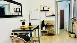 A compact living space with a dining area, a kitchenette, and a hallway leading to a bathroom. - Basic Interior Apartment Sagrada Familia (Barcelona)