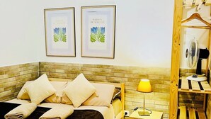 A bedroom with two beds, a wooden headboard, a bedside table with a lamp, and a wooden wardrobe with hanging space. - Basic Interior Apartment Sagrada Familia (Barcelona)