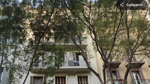 A multi-story building with balconies, a closed shop with graffiti, and a no parking sign. - Basic Interior Apartment Sagrada Familia (Barcelona)