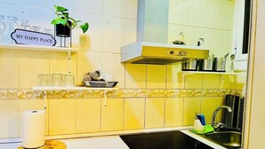 A kitchen with a white countertop, a black sink, a yellow backsplash, and a sign that reads "MY HAPPY PLACE". - Basic Interior Apartment Sagrada Familia (Barcelona)