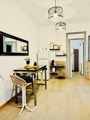 Een moderne keuken met een eethoek, met een houten tafel, stoelen, een hanglamp en een koelkast.