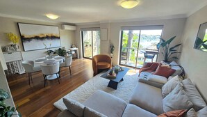 Amplia sala de estar con sofá, una mesa de comedor con sillas y un gran ventanal con vistas al exterior.