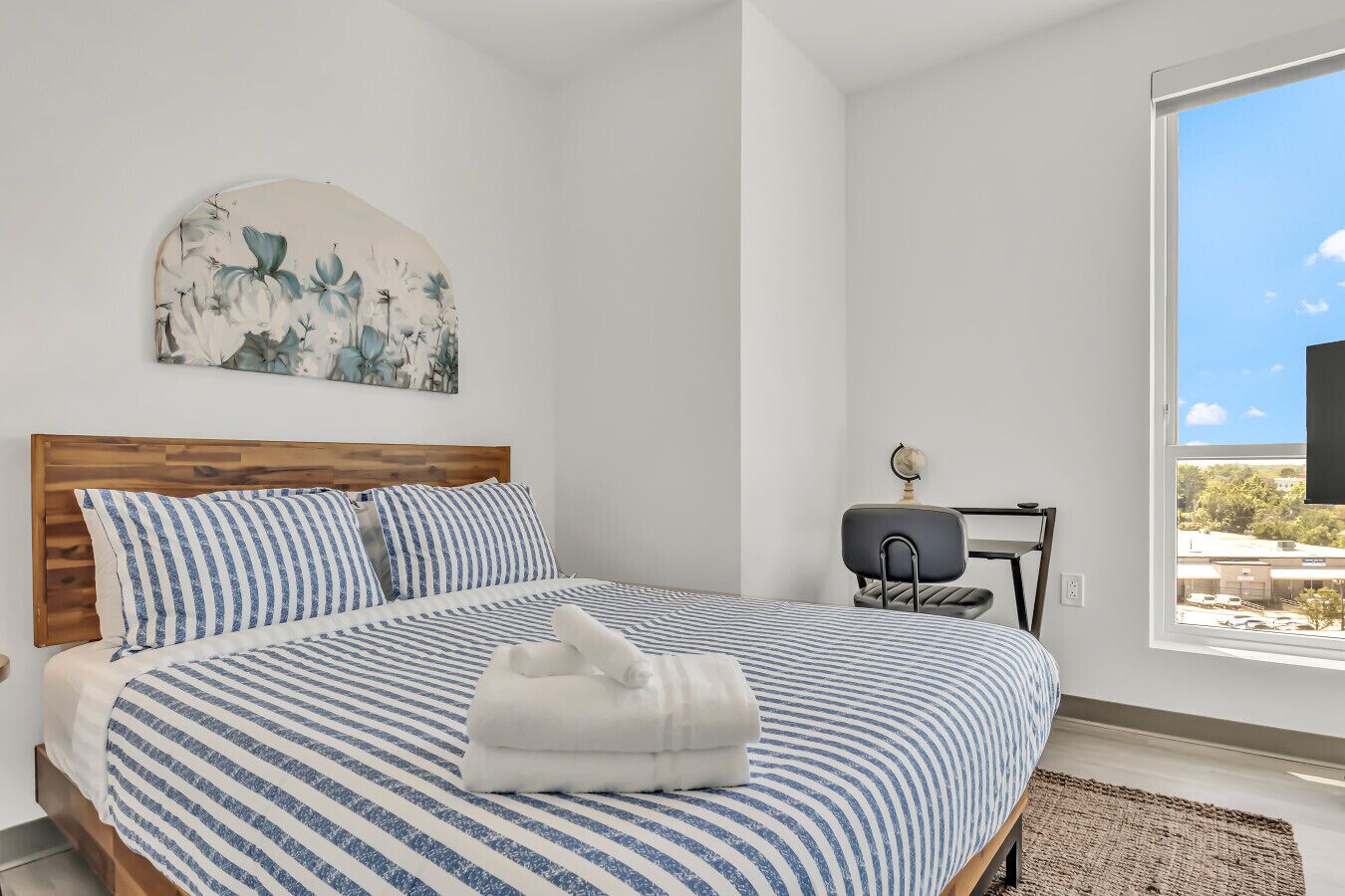 A bedroom with a bed, a desk, and a window.