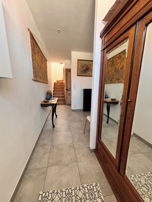 A hallway with a wooden cabinet, a staircase, and a painting on the wall.