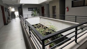 Interior com vários níveis, um pátio central, corrimãos e escadas.